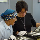 Photo de l'aîné Abraham Ulayuruluk et Joanna Quassa regardant un album photos d'Inuits dans les collections de Bibliothèque et Archives Canada, Ottawa, octobre 2005