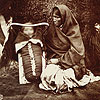 Photograph of an unidentified Ojibwa mother tending to her baby in a carrier, Red River Settlement, Manitoba, 1858