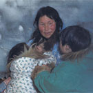 Photograph of an Inuit woman and children cooking in their igloo, Arviat (formerly Eskimo Point) or possibly the Western Arctic, Nunavut, 1937
