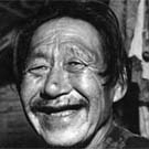 Photograph of a smiling Inuit man in a plaid shirt, unknown location, Nunavut, circa 1950s