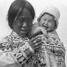 Photograph of an Inuit woman carrying a crying child, unknown location, Nunavut, circa 1926-1943