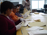 Photograph showing Nunavut residents. Left to right: Sylvia Ivalu, Elders Louis Uttak and Abraham Ulayuruluk, as well as Jesse Mike, at Library and Archives Canada, Ottawa, looking through photographs from the Baffin (Qikiqtaaluk) and Kivalliq (formerly Keewatin) regions, October 2005